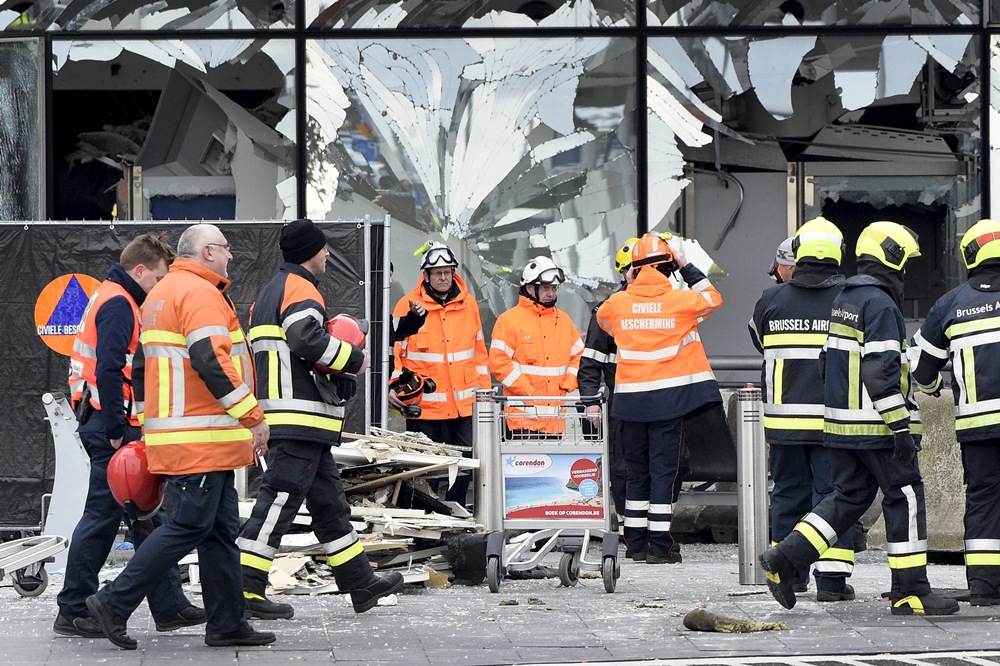 Efectivos de emergencias trabajan en el aeropuerto de Bruselas; en el recuadro, Valls, Michel y Juncker. / REUTERS