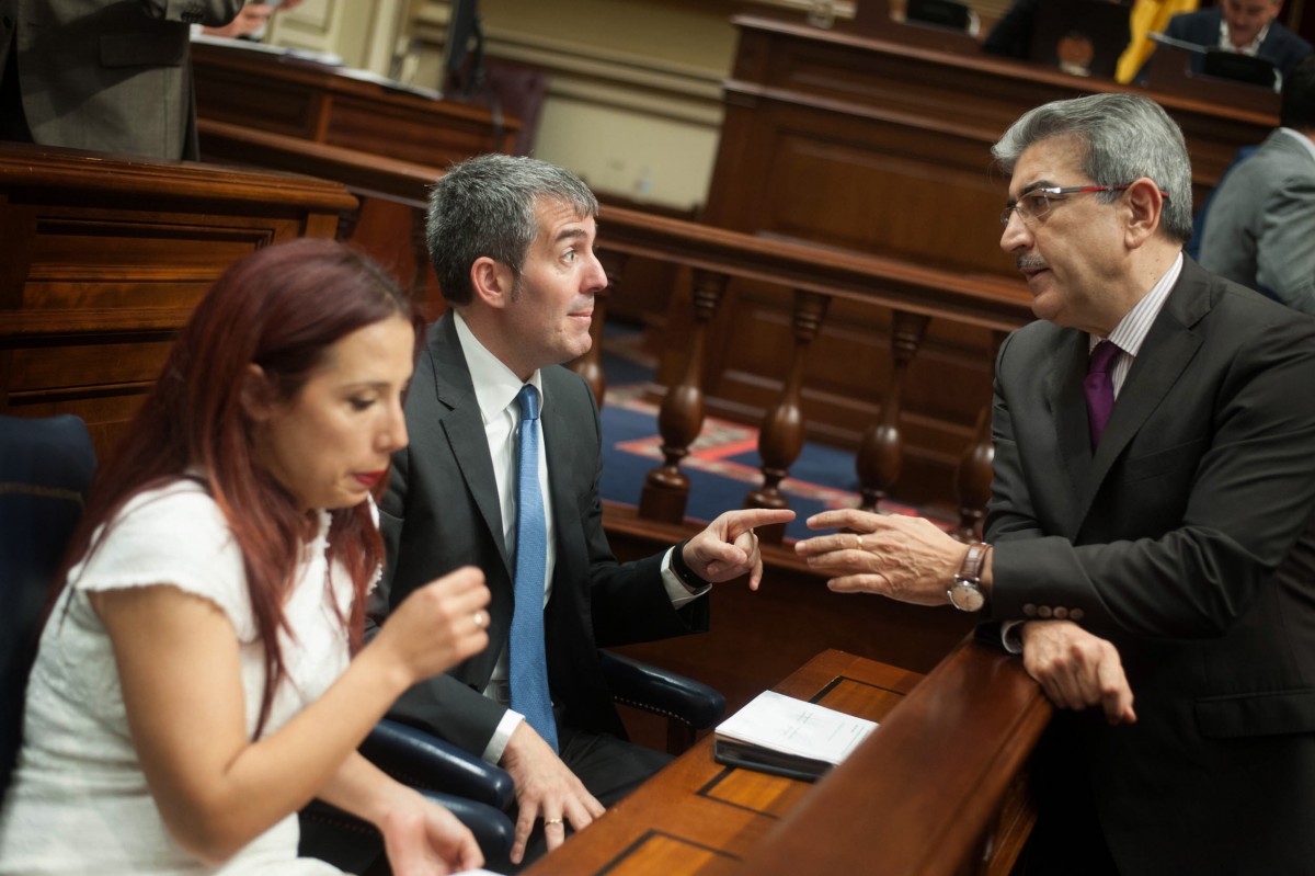 El portavoz parlamentario de Nueva Canarias, Román Rodríguez, conversa con Fernando Clavijo en presencia de Patricia Hernández. / FRAN PALLERO