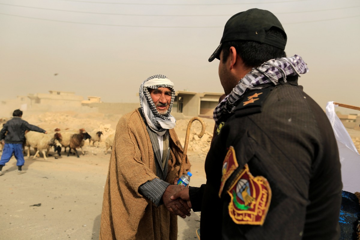 Un habitante local saluda con un miembro de la coalición en un punto de control al este de Mosul, Irak | FOTO: REUTERS/Zohra Bensemra