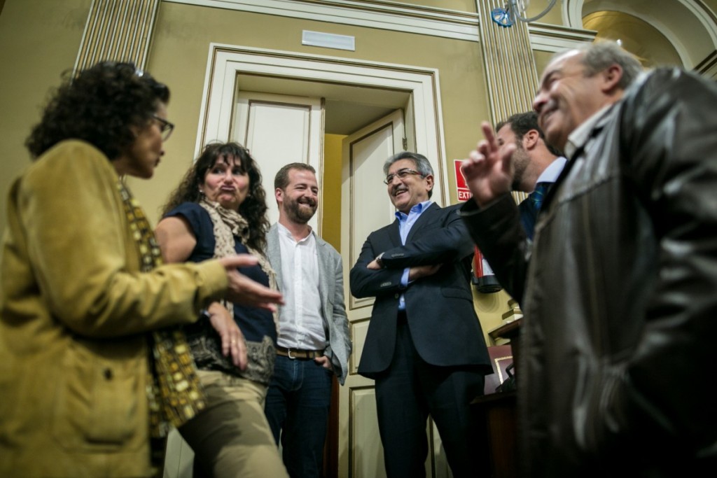 El portavoz de NC, Román Rodríguez, charla con integrantes del Grupo de Podemos, en el salón de sesiones del Parlamento | FOTO: Andrés Gutiérrez