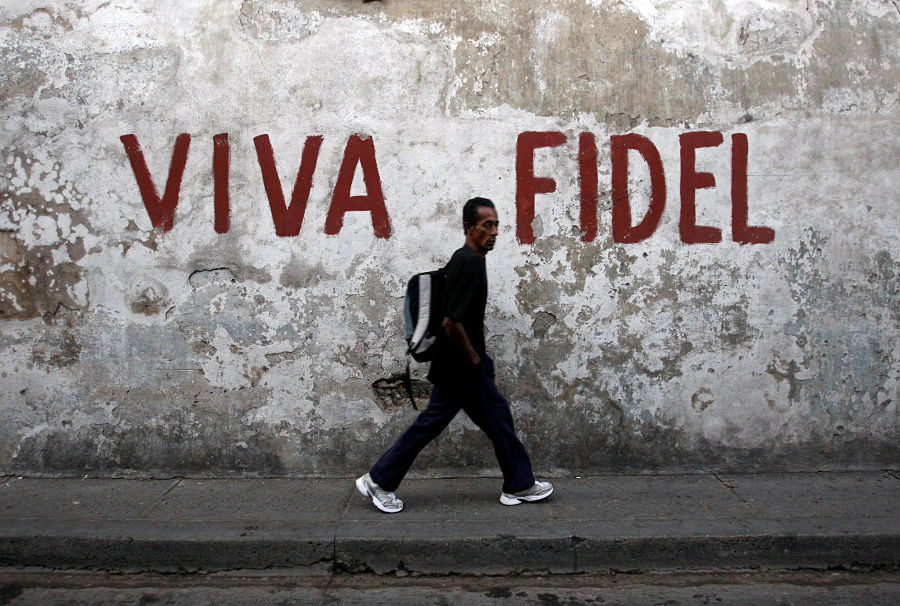 Un hombre camina frente de un graffiti con el lema "VIVA FIDEL" en Santiago de Cuba | REUTERS/Claudia Daut