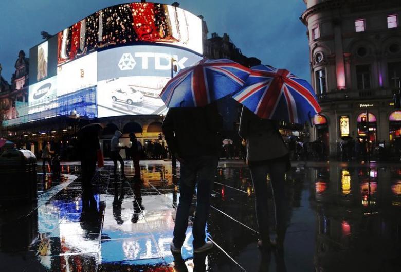 Varias personas observan de noche las luces de los carteles luminosos de Piccadilly Circus, en Londrés | REUTERS