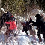 Momento en que varios policías canadienses ayudan a refugiados a huir de los agentes fronterizos estadounidenses | REUTERS/Christinne Muschi