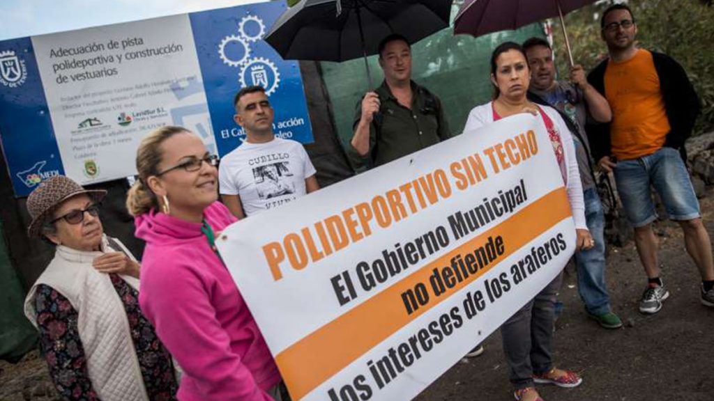 Miembros del colectivo, ayer con pancartas y paraguas a las afueras del polideportivo / A. GUTIÉRREZ