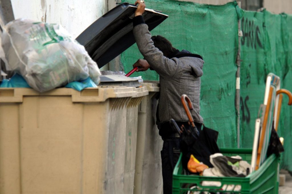 Una persona sin techo rebusca en un contenedor de basura en Tenerife. / DA