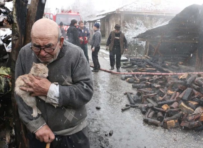 Ali, sujetando al gatito frente a los restos de su casa quemada. / METRO