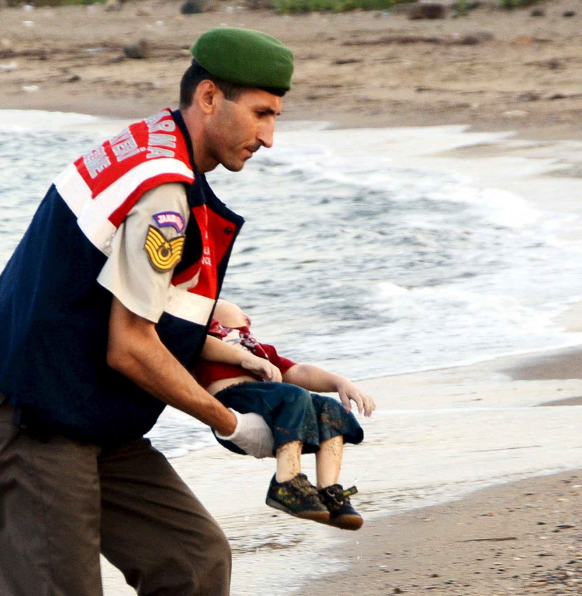 Aylan, muerto en brazos de un oficial. / EP