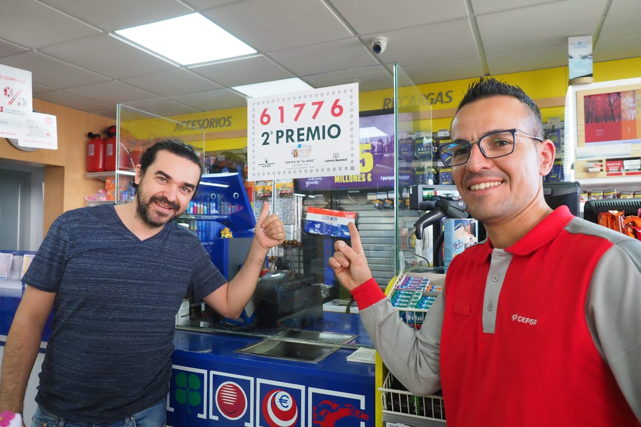 Empleados de la gasolinera CEPSA de Las Galletas posan con el número premiado en el sorteo del Niño vendido en el establecimiento / Sergio Méndez