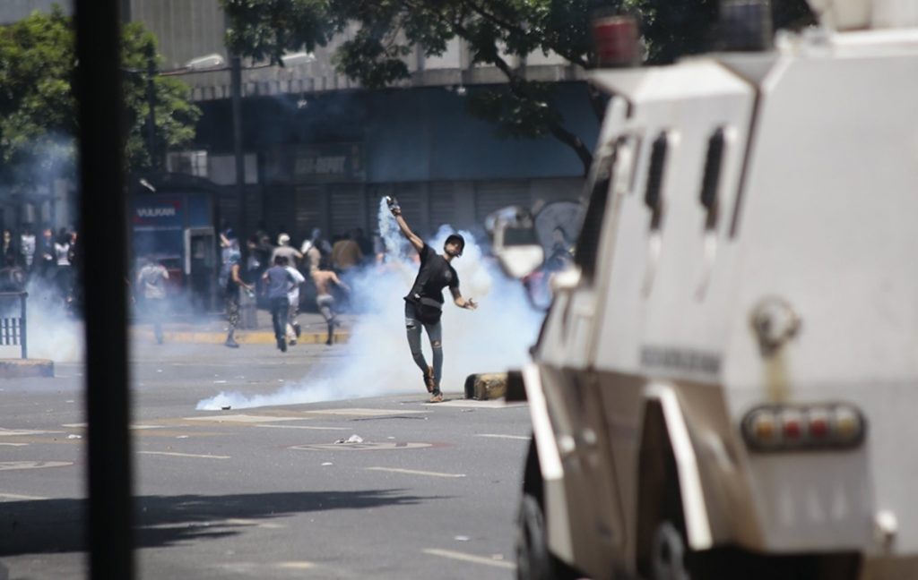 Un seguidor de Guaidó lanza un bote de humo contra la Guardia Nacional, ayer en Caracas. Rafael Hernández (DPA)