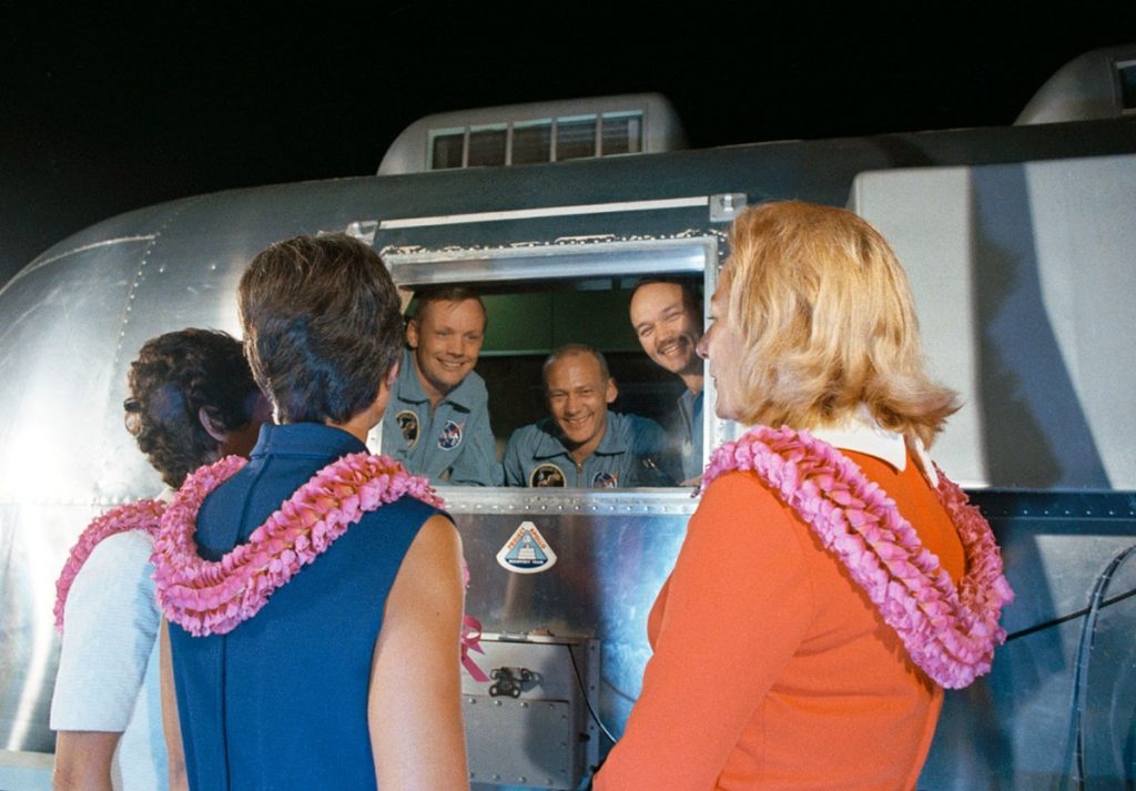 Confinados en el MQF, Armstrong, Aldrin y Collins reciben la visita de sus esposas tras aterrizar en la base de la Fuerza Aérea de Ellington, en Houston. NASA