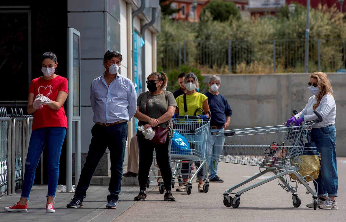 Varias personas protegidas con mascarillas hacen cola en la entrada de un supermercado. EFE/Julio Muñoz/Archivo