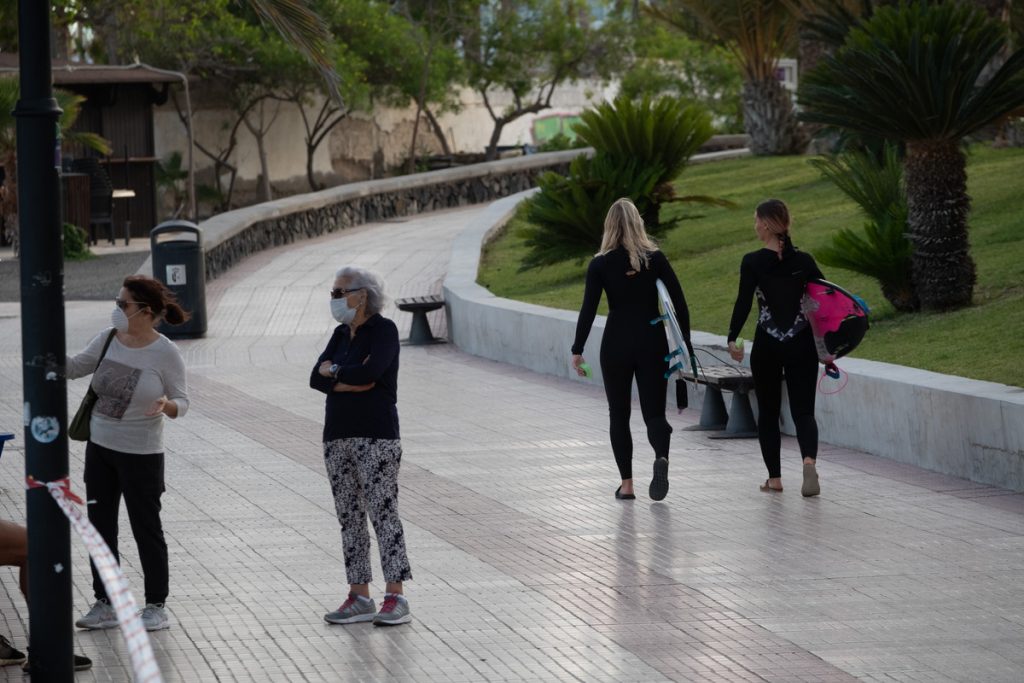 Surfistas caminan por el paseo de Las Américas camino de las olas, cuando cae la tarde. / FRAN PALLERO
