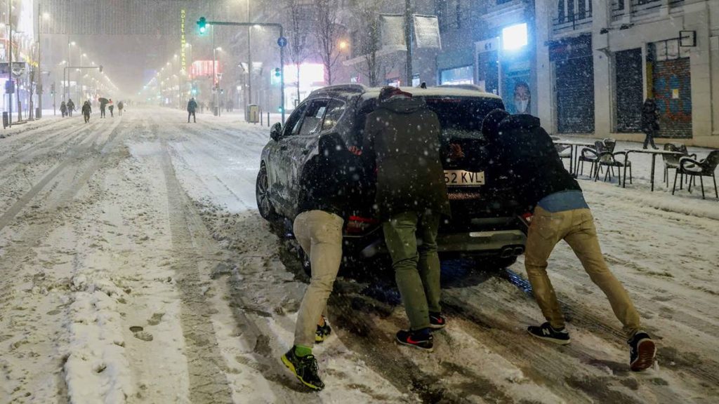 Imagen de unas personas en Madrid empujando un coche que ha perdido la tracción. EFE