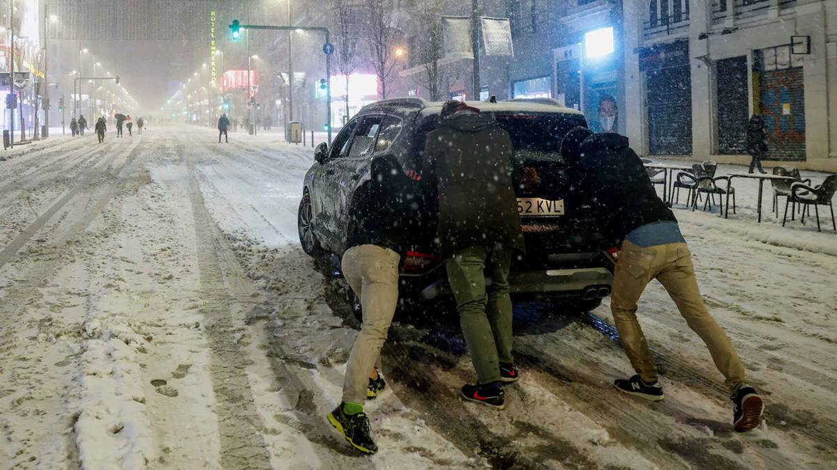 Imagen de unas personas en Madrid empujando un coche que ha perdido la tracción. EFE