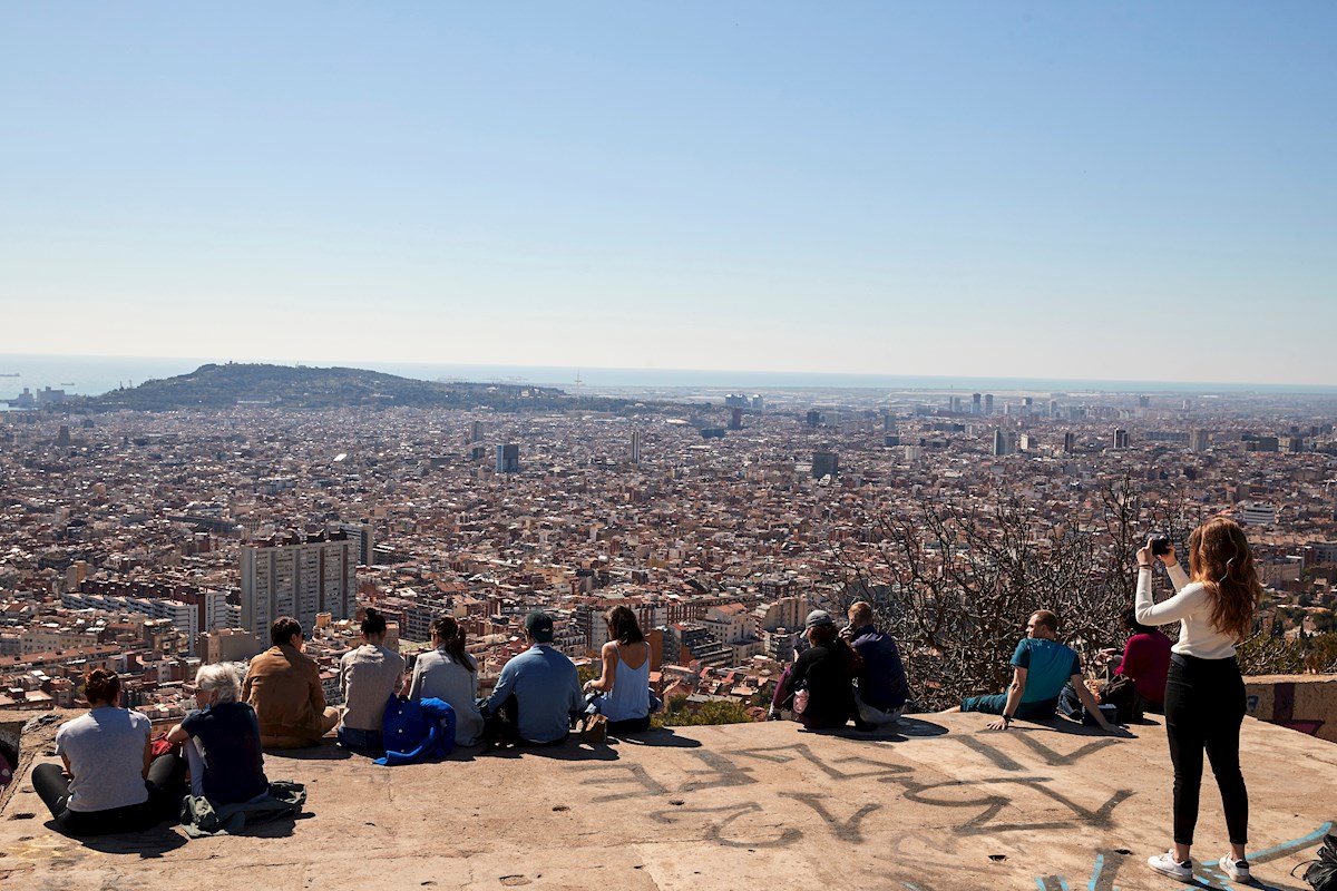 Varias personas observan el paisaje mientras visitan los búnker del Turó de la Rovira este domingo en Barcelona. Alejandro García (EFE)