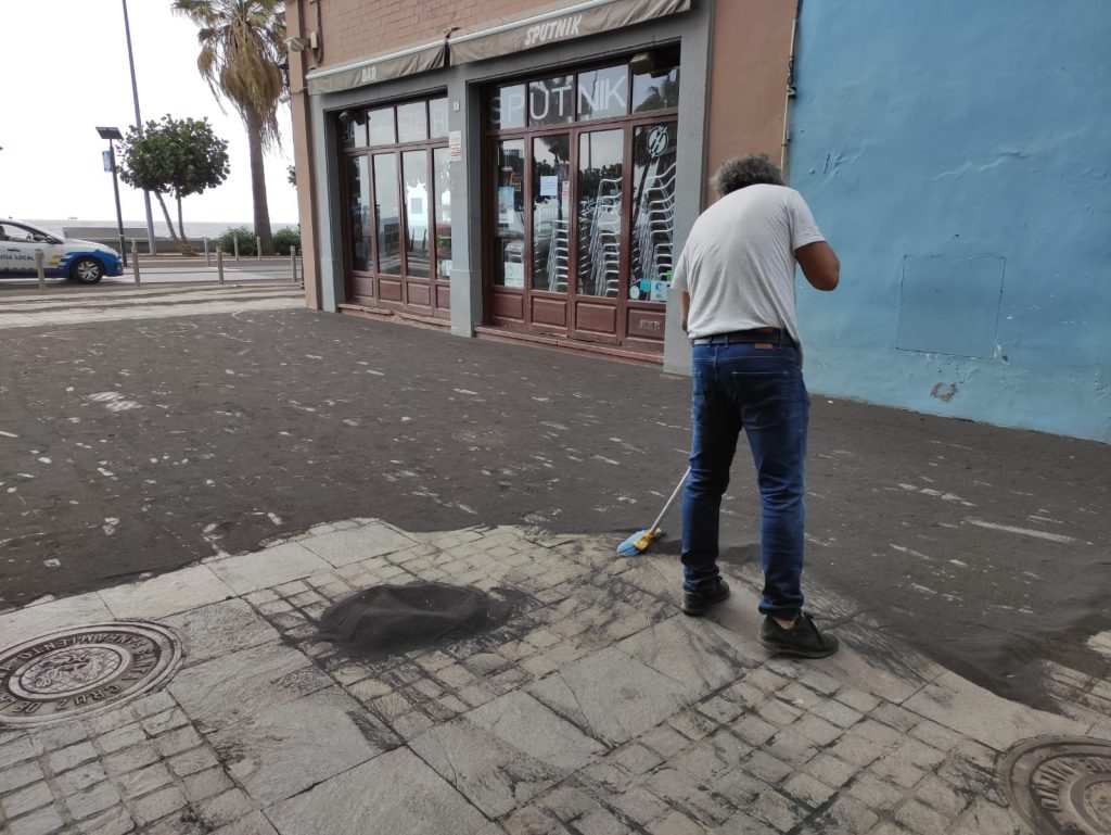 Estampa mañanera ayer en Santa Cruz de La Palma, con las calles cubiertas de ceniza, los comerciantes                   barriendo las vías y los operarios municipales retirando bolsas de polvo.  Danios