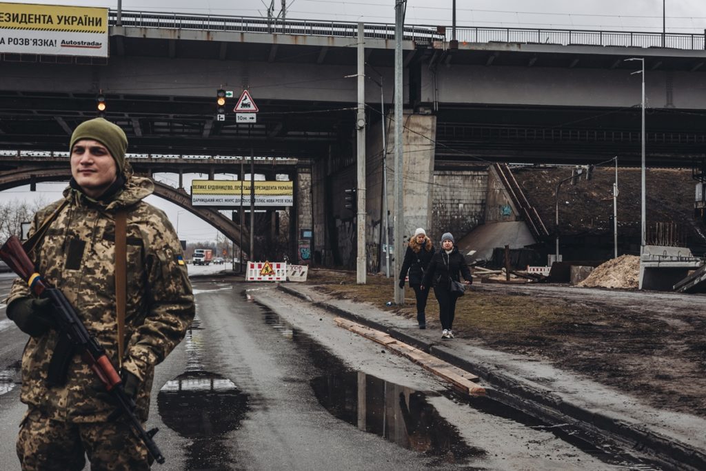 Dos mujeres caminan frente a un miliciano ucraniano, a 2 de marzo de 2022, en Kiev (Ucrania). Europa Press