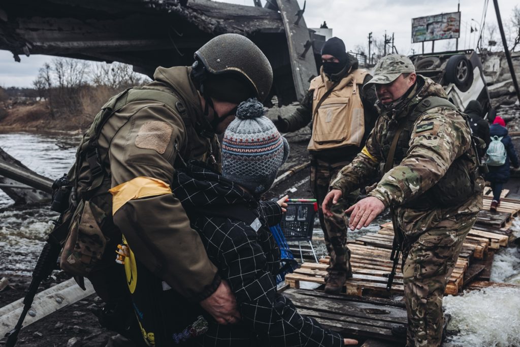 Unos soldados ayudan a cruzar el río a un niño, a 7 de marzo de 2022, en Irpin (Ucrania). Europa Press