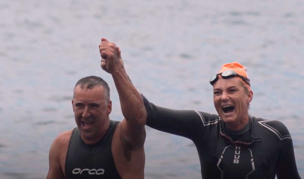 Dos parcipantes alzan los brazos como victoria al concluir la travesía a nado de las playas de Aridane