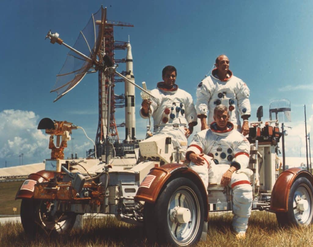 Desde la izquierda, Schmitt, Evans y Cernan (sentado) en un róver lunar de entrenamiento. Al fondo, su Saturno V.