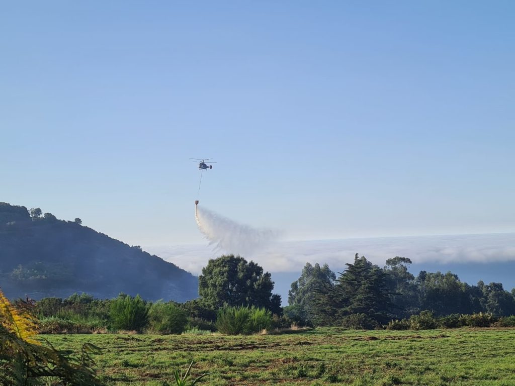 Un helicóptero realiza una descarga de agua durante la extinción de un incendio forestal en la isla de Tenerife