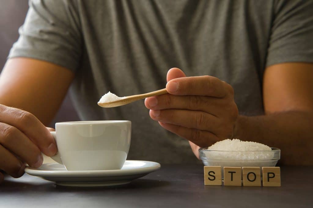 Un hombre le echa azúcar a su bebida. Shutterstock
