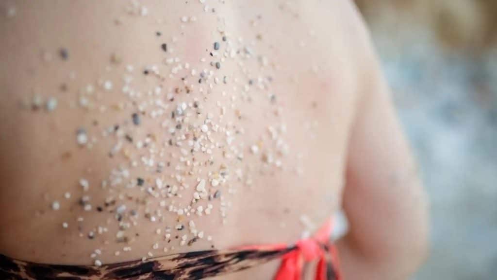 La espalda de una mujer en bikini con arena pegada después de un día de playa / iStock