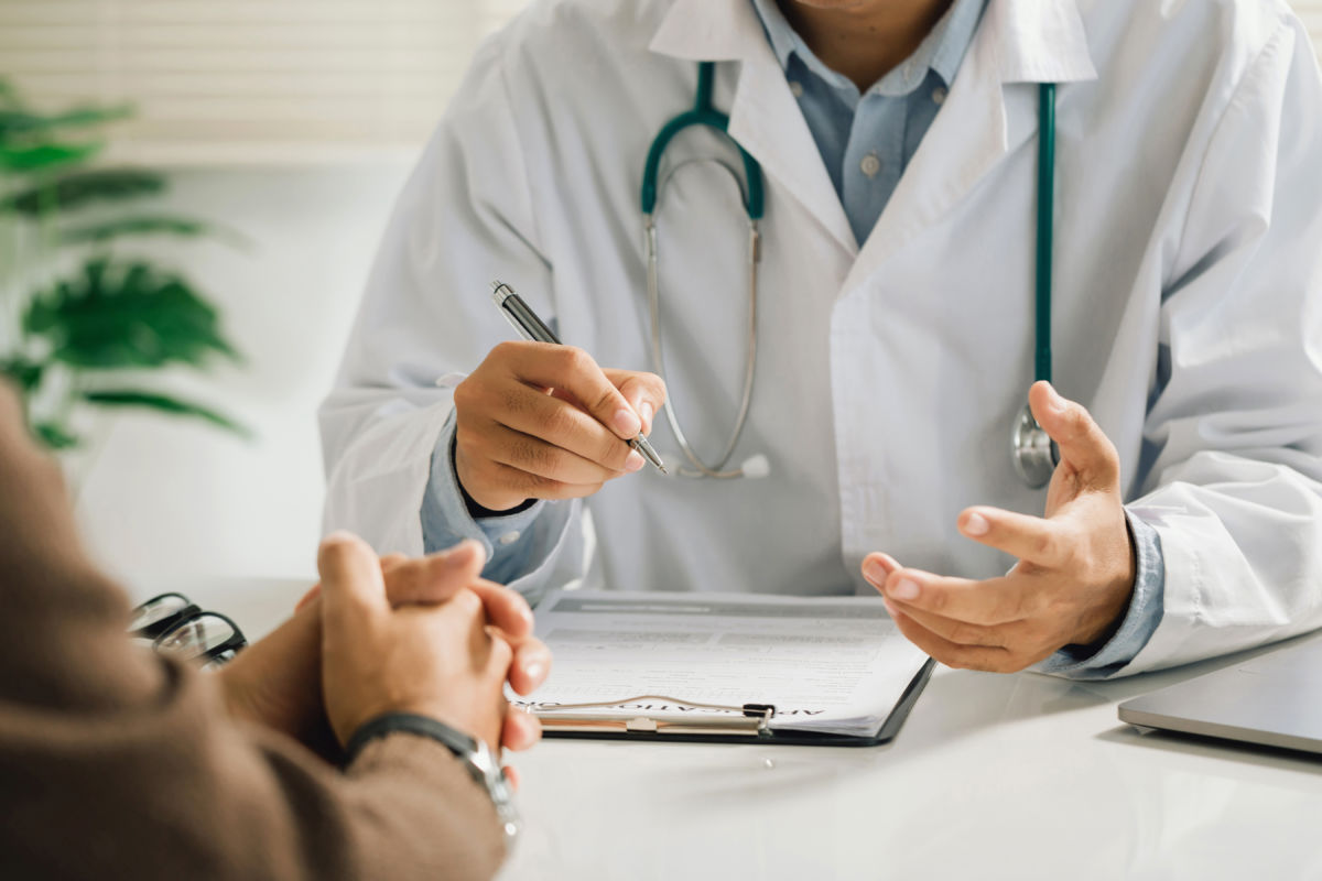 Un médico comenta los resultados o síntomas y recomendaciones con un paciente y firma un documento médico durante una consulta en la clínica