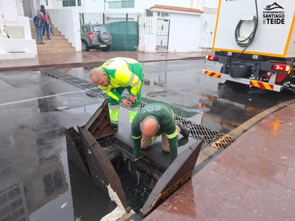 Operarios comprueban si los imbornales están obstruidos.