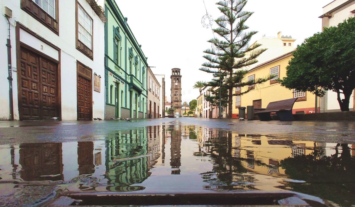 Foto de archivo de la Torre de la Concepción en San Cristóbal de La Laguna, Tenerife, bajo un cielo nuboso con un charco de lluvia en el suelo en primer plano.