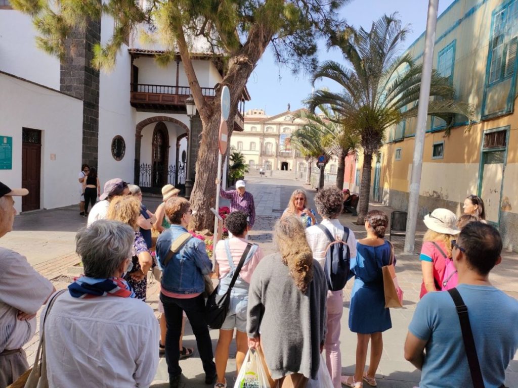 Grupo de personas atendiendo a una explicación junto a un árbol de gran porte en el centro de Santa Cruz de Tenerife