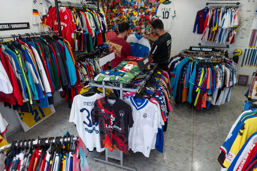 Luis Martín enseña una chaqueta del CD Tenerife a un cliente en la tienda Football Fútbol Club, en Tenerife
