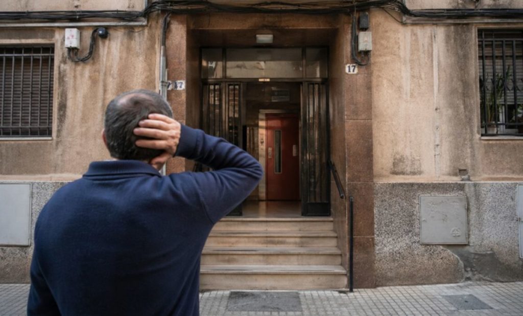 Vecino preocupado por derrama de ascensor antiguo en un portal de viviendas por nueva normativa 2026