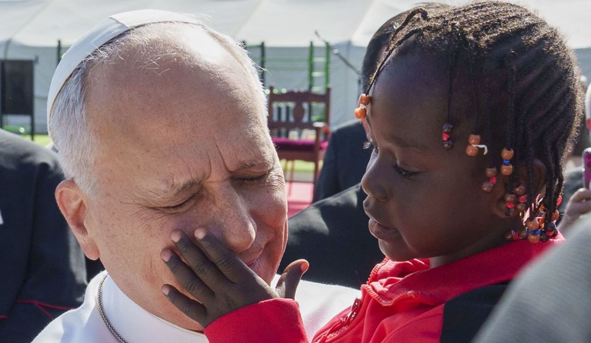 El papa León XIV coge en brazos a una niña migrante en Las Raíces, en La Laguna. | Ramón de la Rocha / Efe