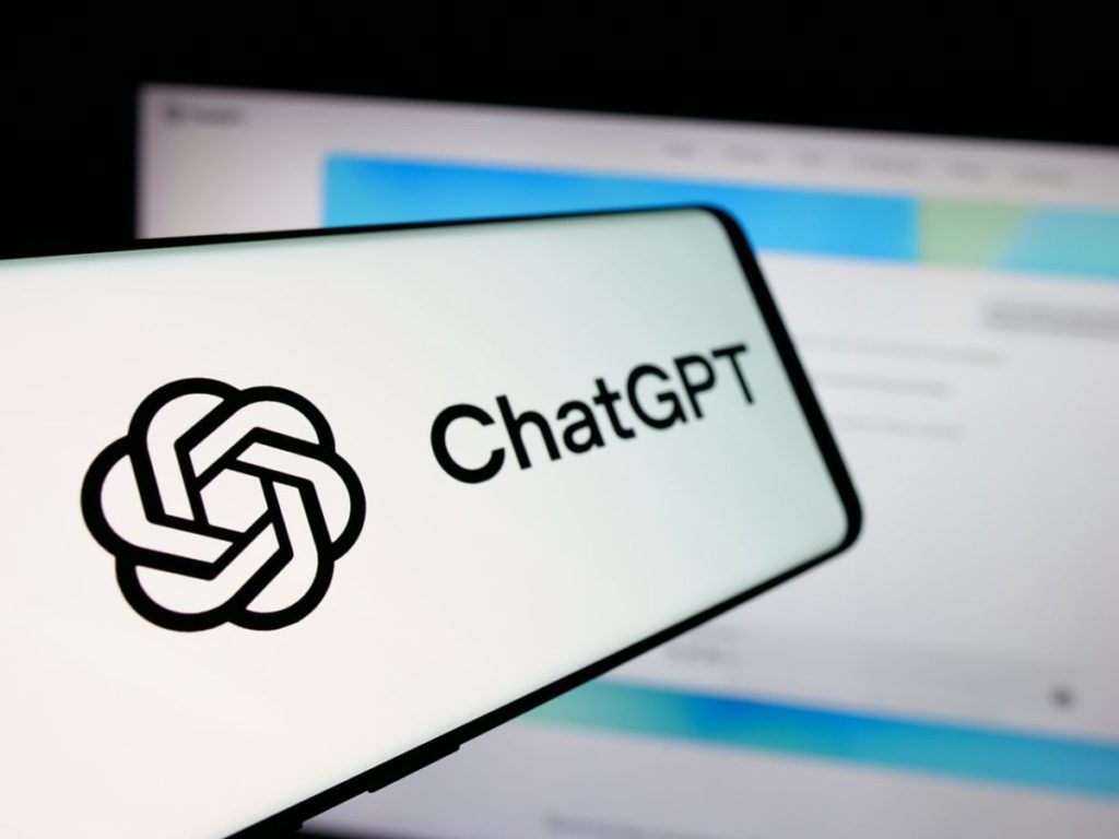 En esta imagen ilustrativa, un teléfono móvil muestra en pantalla el logotipo de ChatGPT, el chatbot de inteligencia artificial generativa de OpenAI, frente a una página web